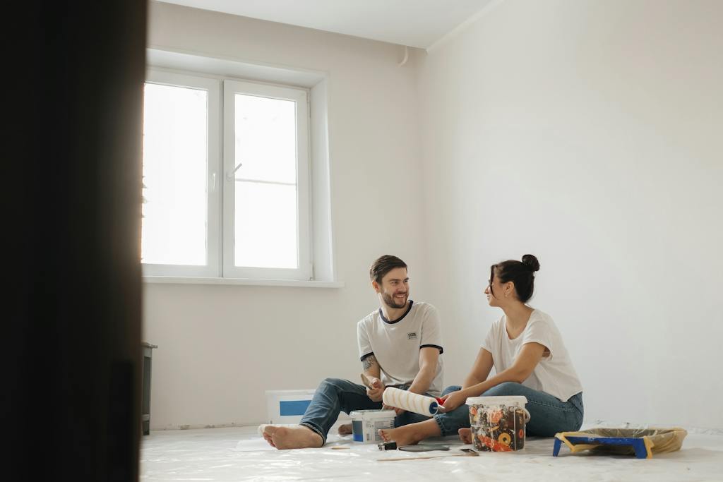 A Couple Sitting on the Floor While Holding Paint Brush DIY home renovating