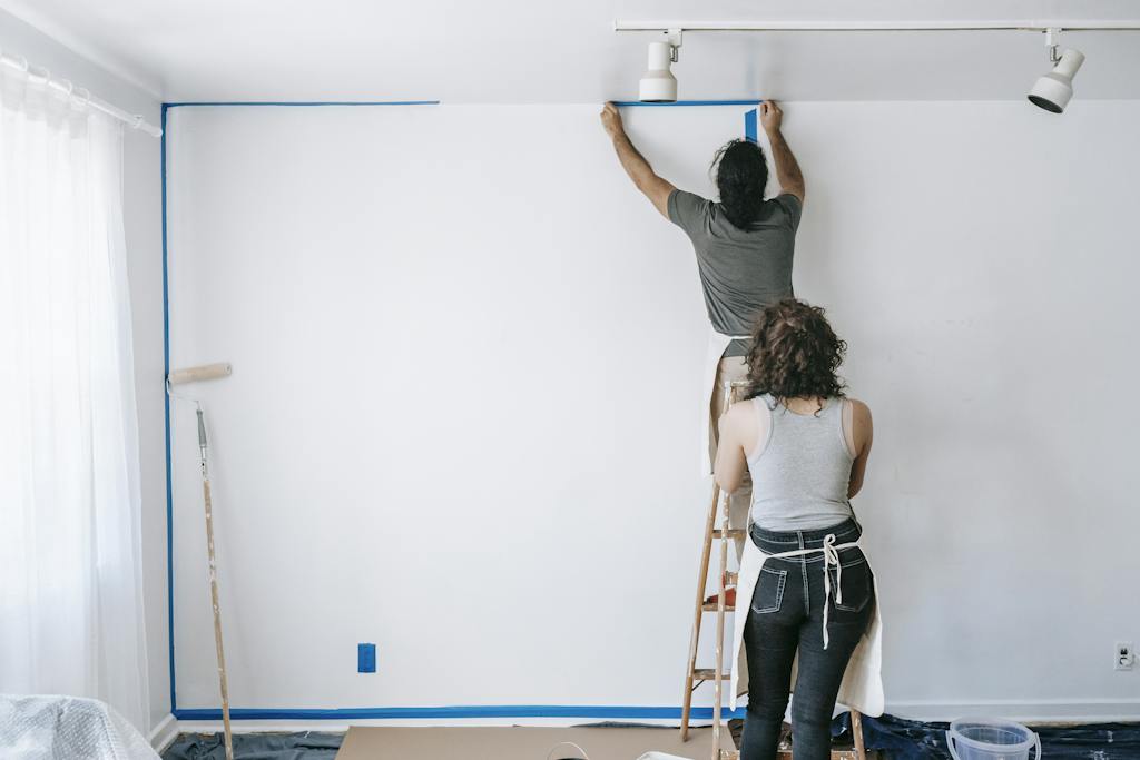 Man Standing On A Stepladder Putting Tape On Wall safely supported